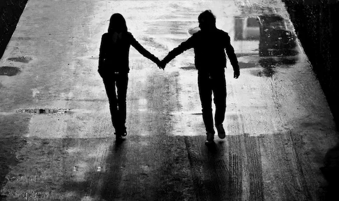 Une photo en noir et blanc d'un couple se tenant la main en marchant la nuit