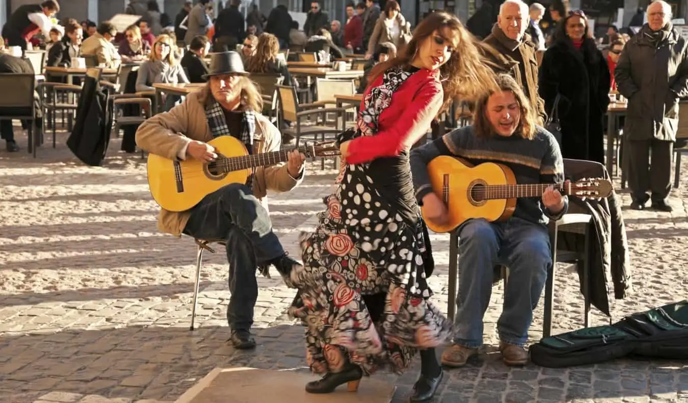 Une femme danse le flamenco accompagnée de deux guitaristes derrière elle sur une place à Madrid, Espagne