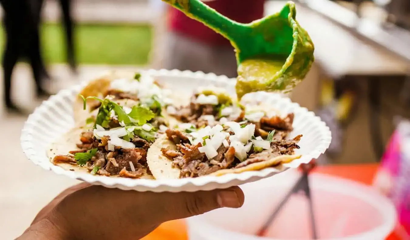 En hånd som holder en papirtallerken full av fersk taco i Mexico City, Mexico
