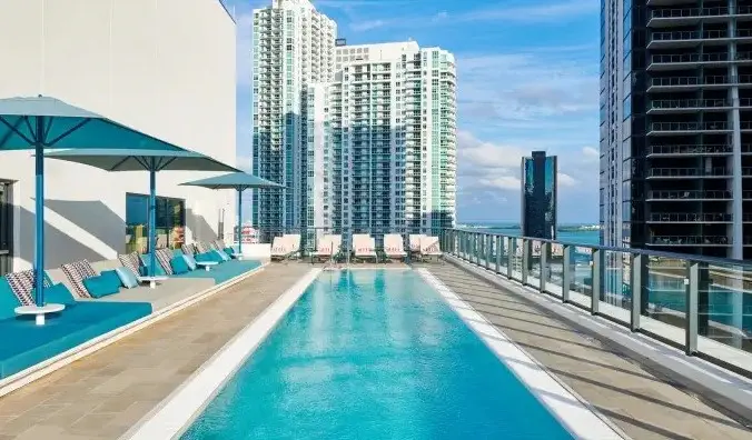Longue piscine rectangulaire sur le toit avec chaises longues au bord de la piscine, entourée des gratte-ciel de Miami, en Floride, à l'hôtel CitizenM Miami Brickell