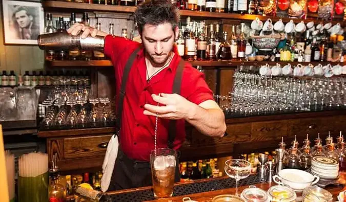 Lidé popíjejí ve spoře osvětleném zákazovém baru zvaném The Dead Rabbit