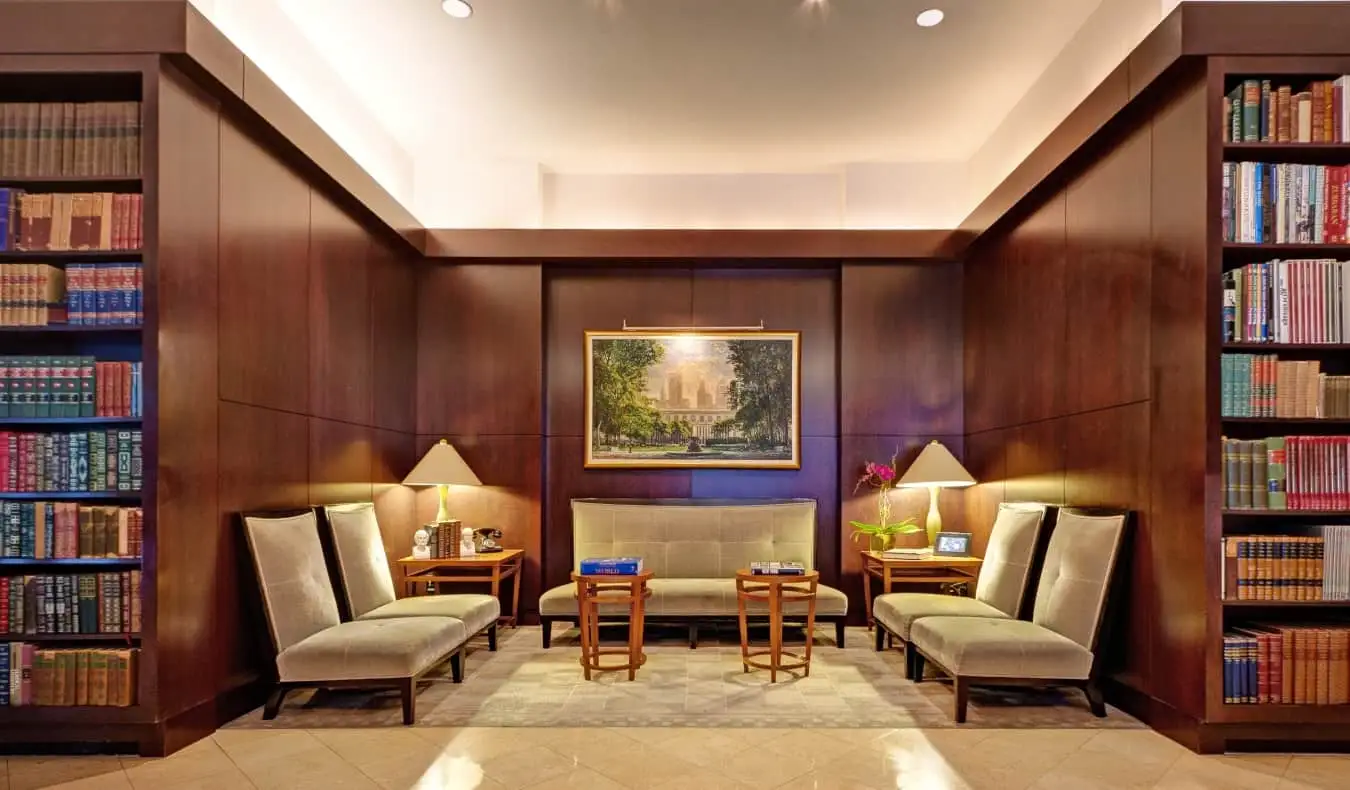 Le hall du Library Hotel à New York, avec un coin salon entouré de bibliothèques du sol au plafond