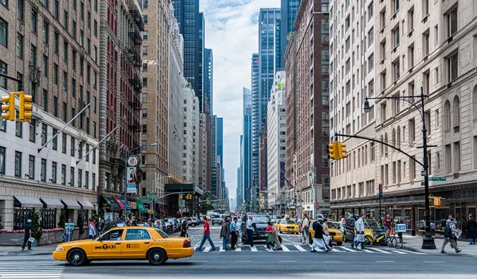 Une intersection très fréquentée avec un taxi jaune à New York avec beaucoup de gens qui traversent la rue