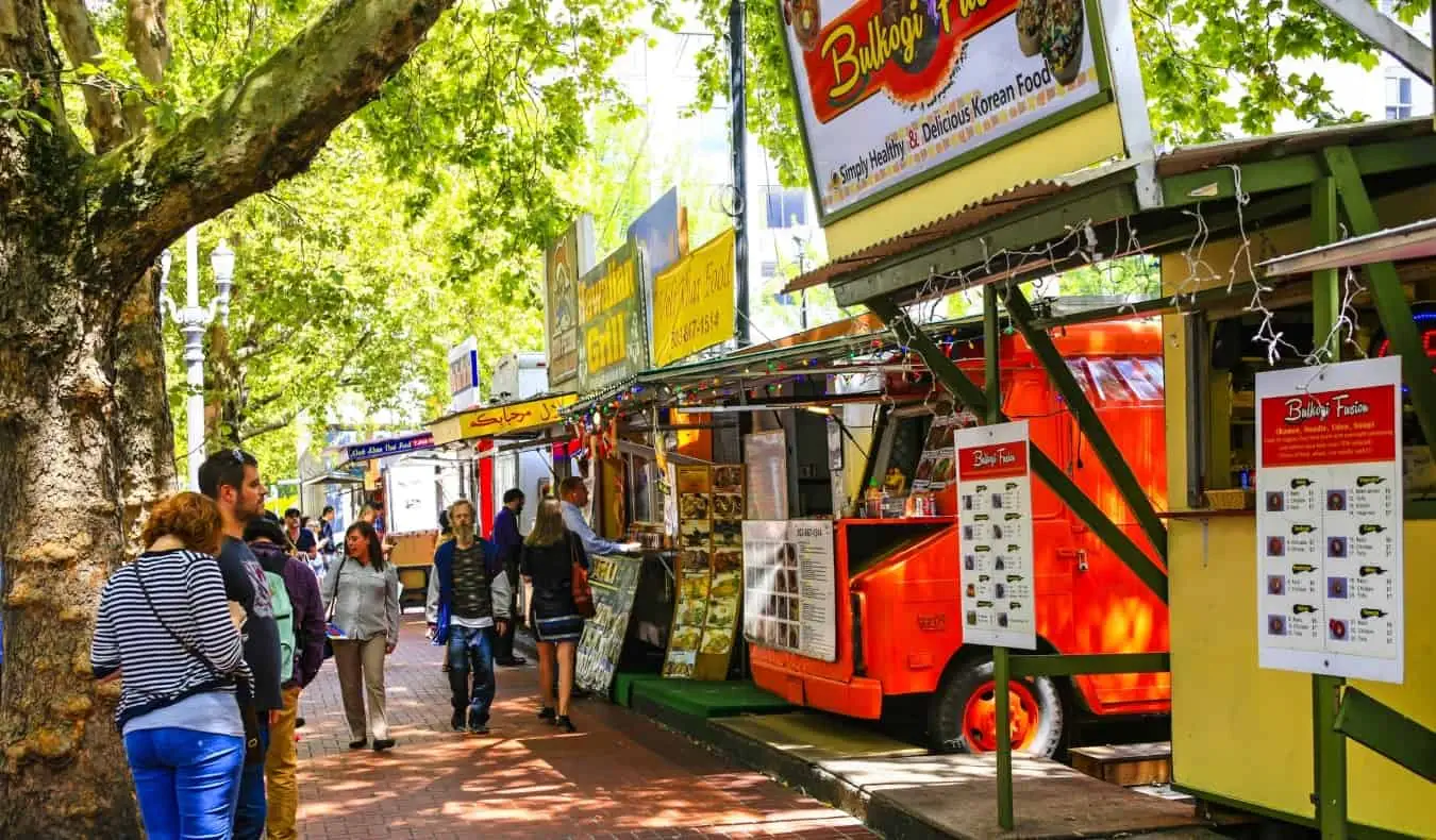 Personnes marchant sur un trottoir en brique bordé de food trucks à Portland, Oregon