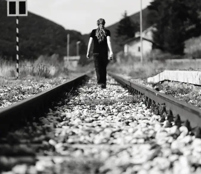 Autorretrato em preto e branco de Laurence andando nos trilhos da ferrovia