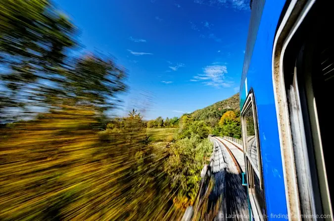 Foto fra et hurtigt tog, der passerer et frodigt landskab