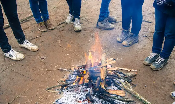 Un groupe de voyageurs solitaires debout autour d'un petit feu de camp