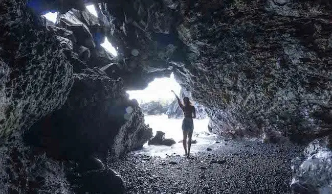 Viajante solitária posando para uma foto em uma caverna perto do oceano