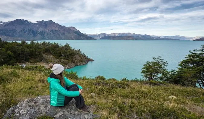 Uma viajante solitária posando em uma doca perto das montanhas
