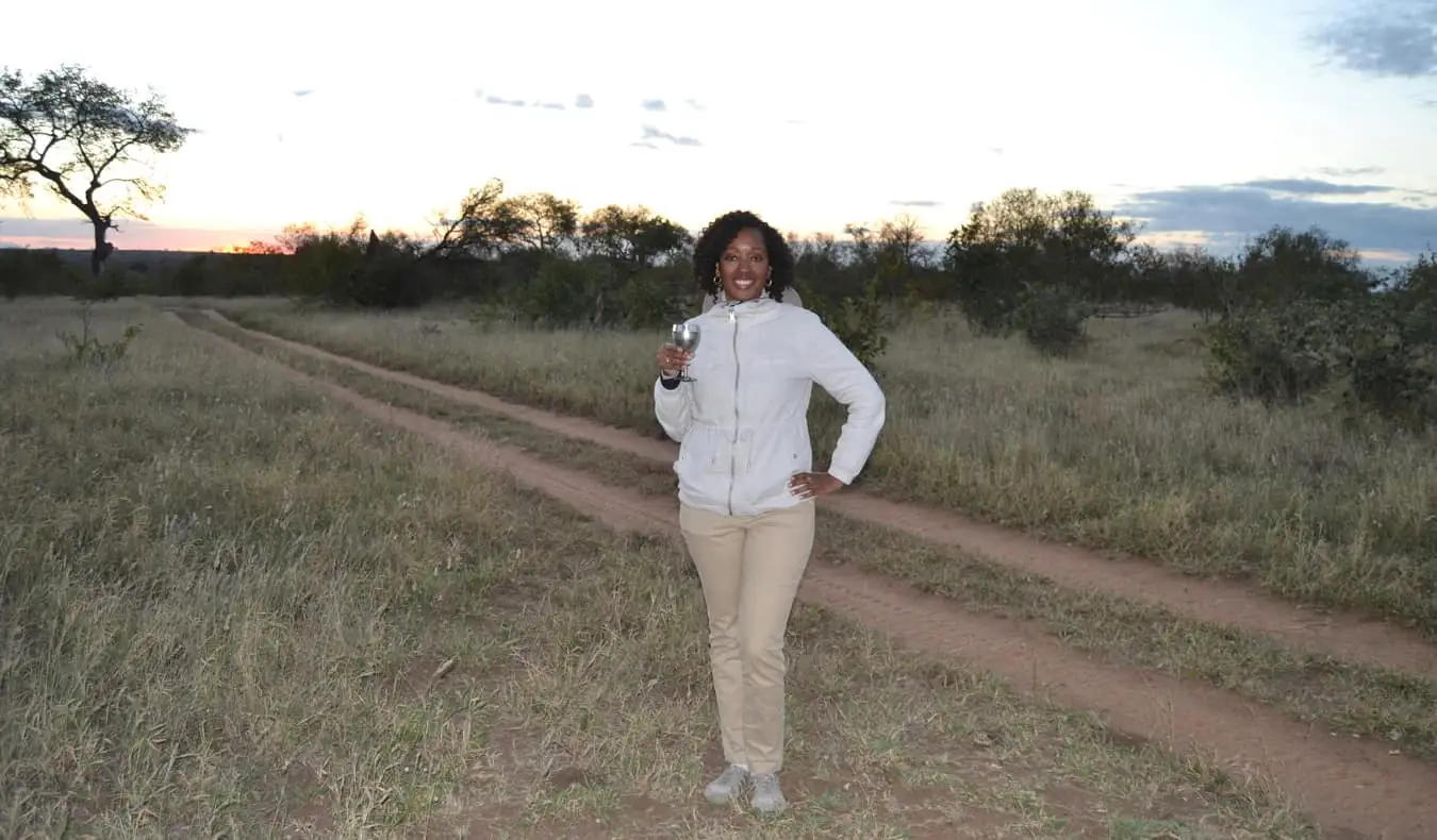 Senitra, een solo zwarte vrouwelijke reiziger die poseert tijdens een safari in Afrika
